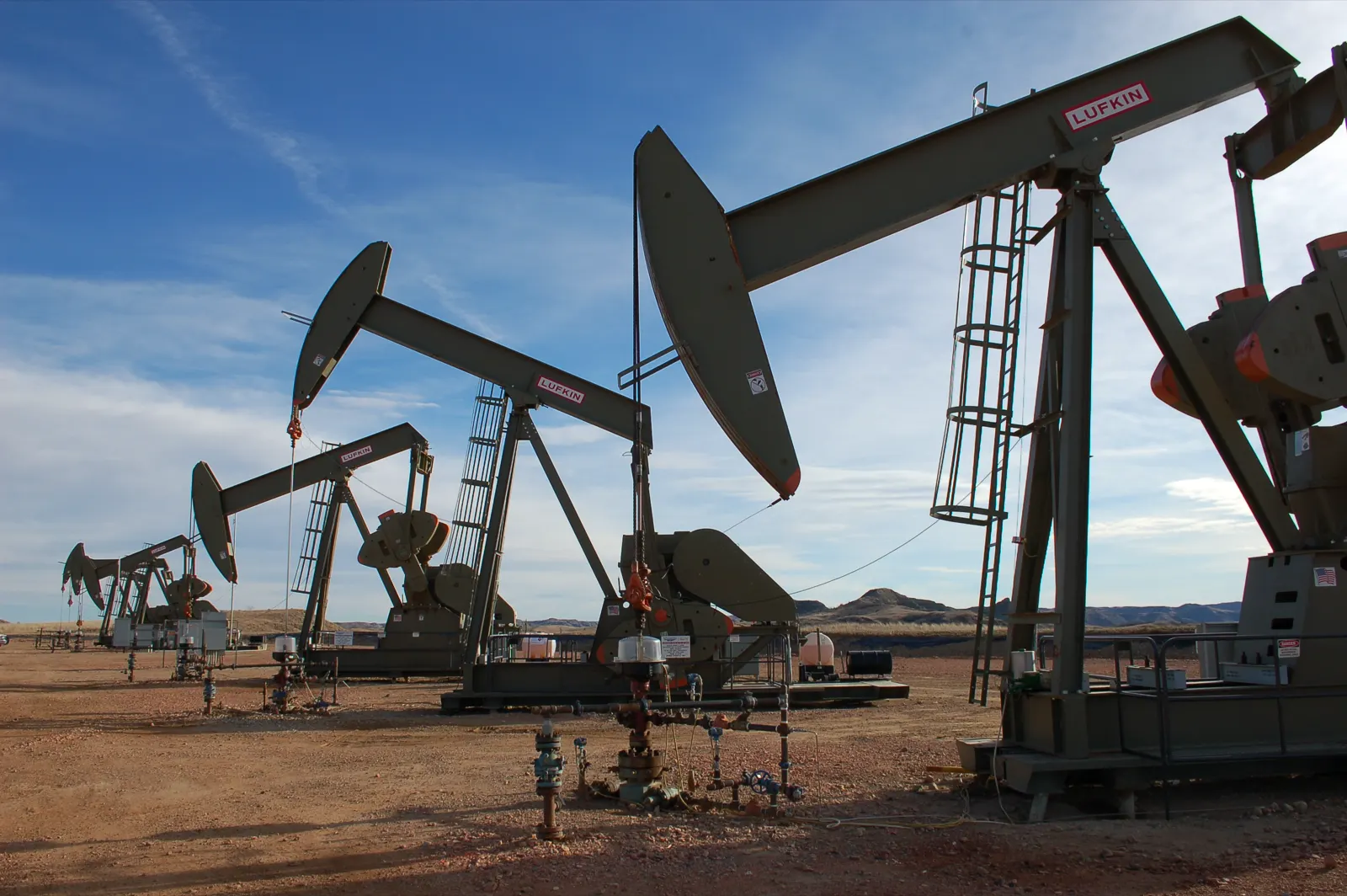 A cluster of pumpjacks at an oil well site on the North Dakota prairie, each one reported well by well to the state