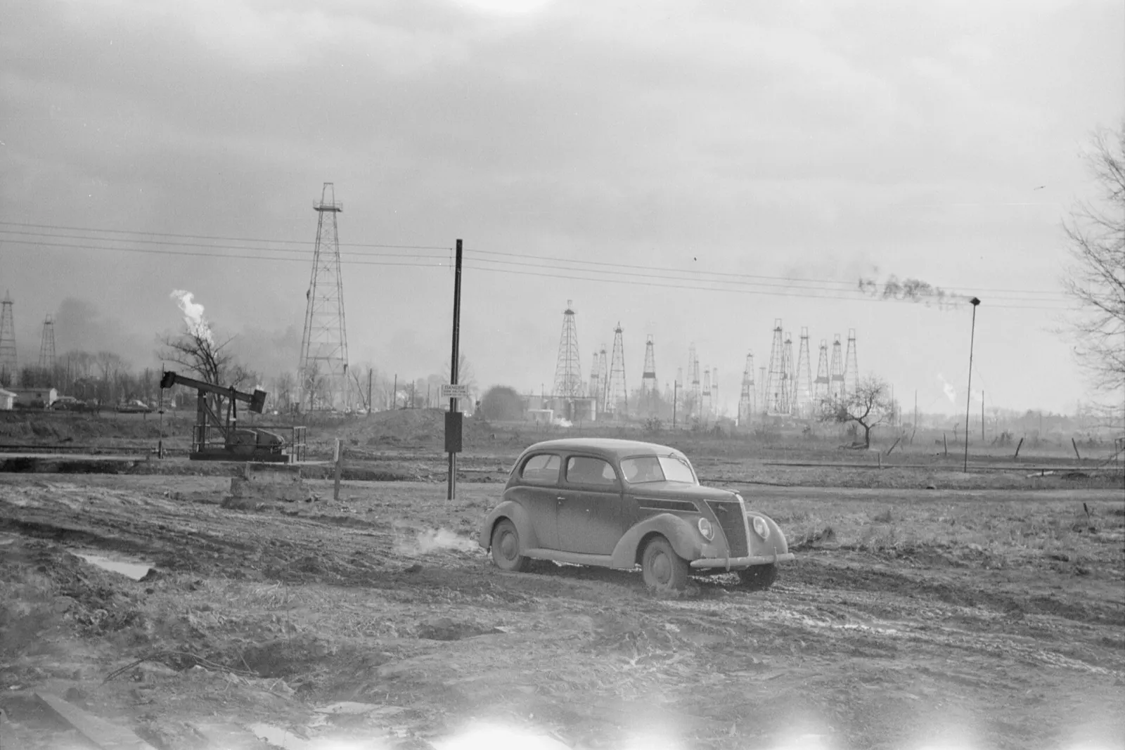 Oil derricks and a 1937 Ford in the Marion County oil field near Salem, Illinois, in February 1940
