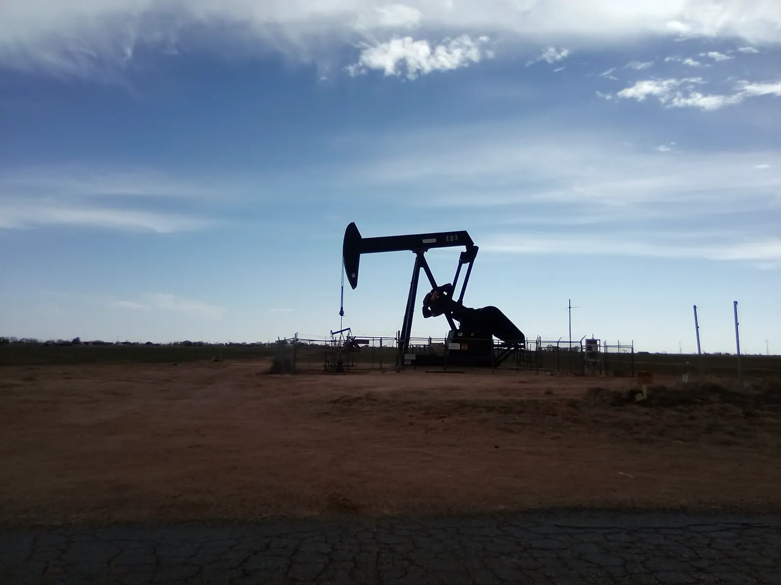 Sell mineral rights in Texas: a pumpjack silhouetted against a wide sky on red dirt near Levelland, Texas