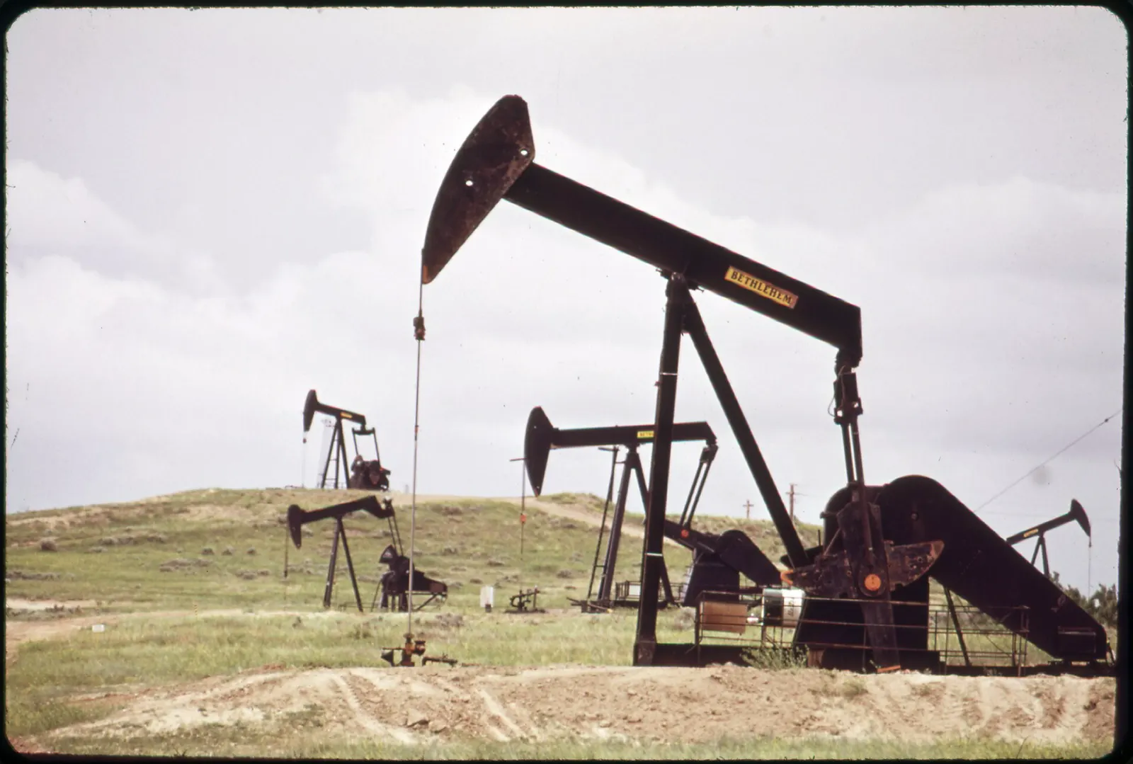 Selling oil rights: pumpjacks working on grassy hills near Teapot Dome, Wyoming